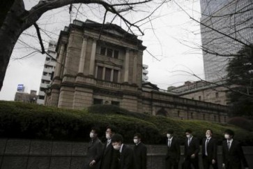 رجال أعمال يسيرون أمام مقر بنك اليابان المركزي.